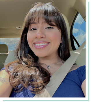 Meet Our Team: A woman with long brown hair and bangs smiles while sitting in a car, wearing a seatbelt and a blue top. Sunlight and blue sky are visible through the window.